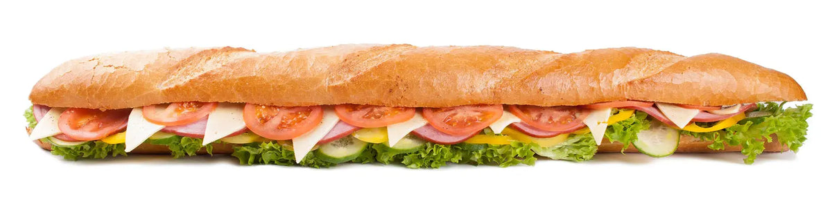 A large baguette-style sub sandwich filled with tomato slices, white cheese, lettuce, cucumber, and melted cheese, isolated on a white background.